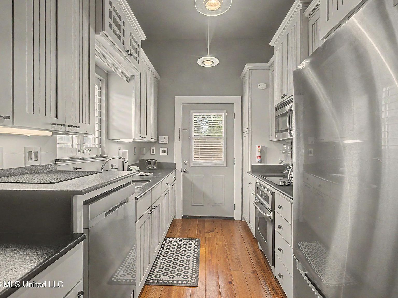 Galley-style kitchen with white cabinetry and heart pine floor