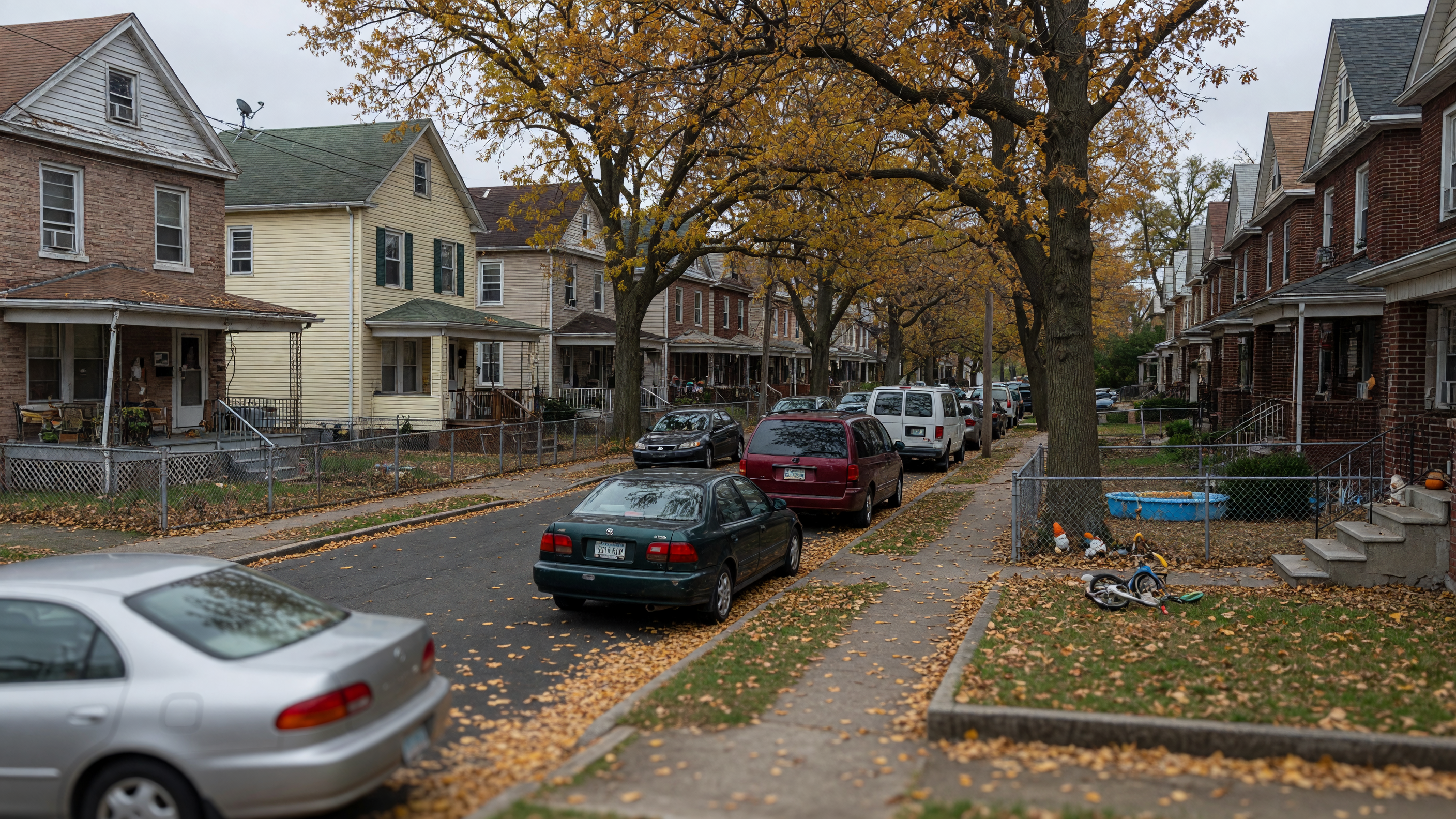 Residential street in Paterson, New Jersey with multi-family homes and mature trees along a quiet block