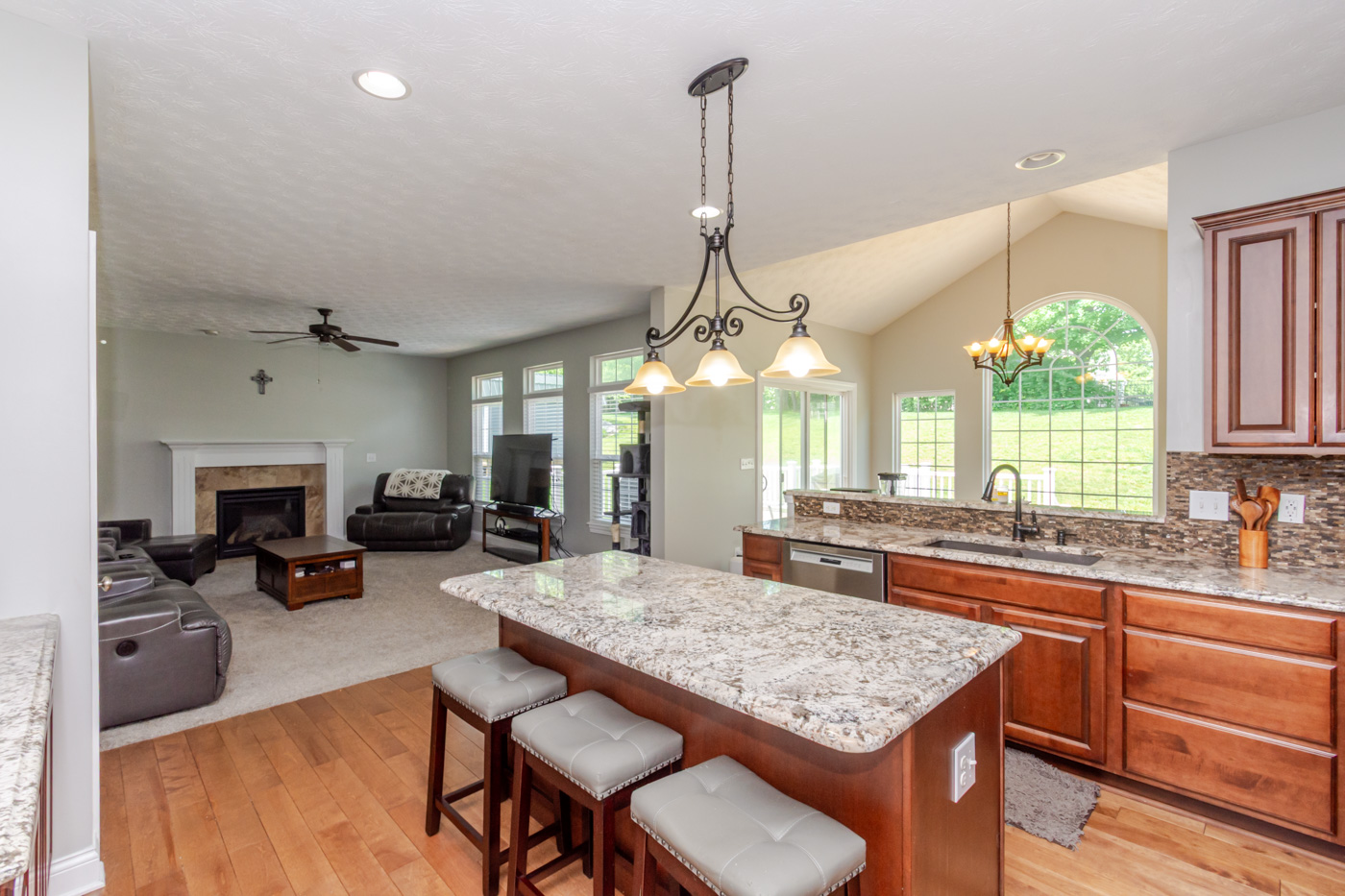 Open-concept kitchen with granite countertops flowing into the family room