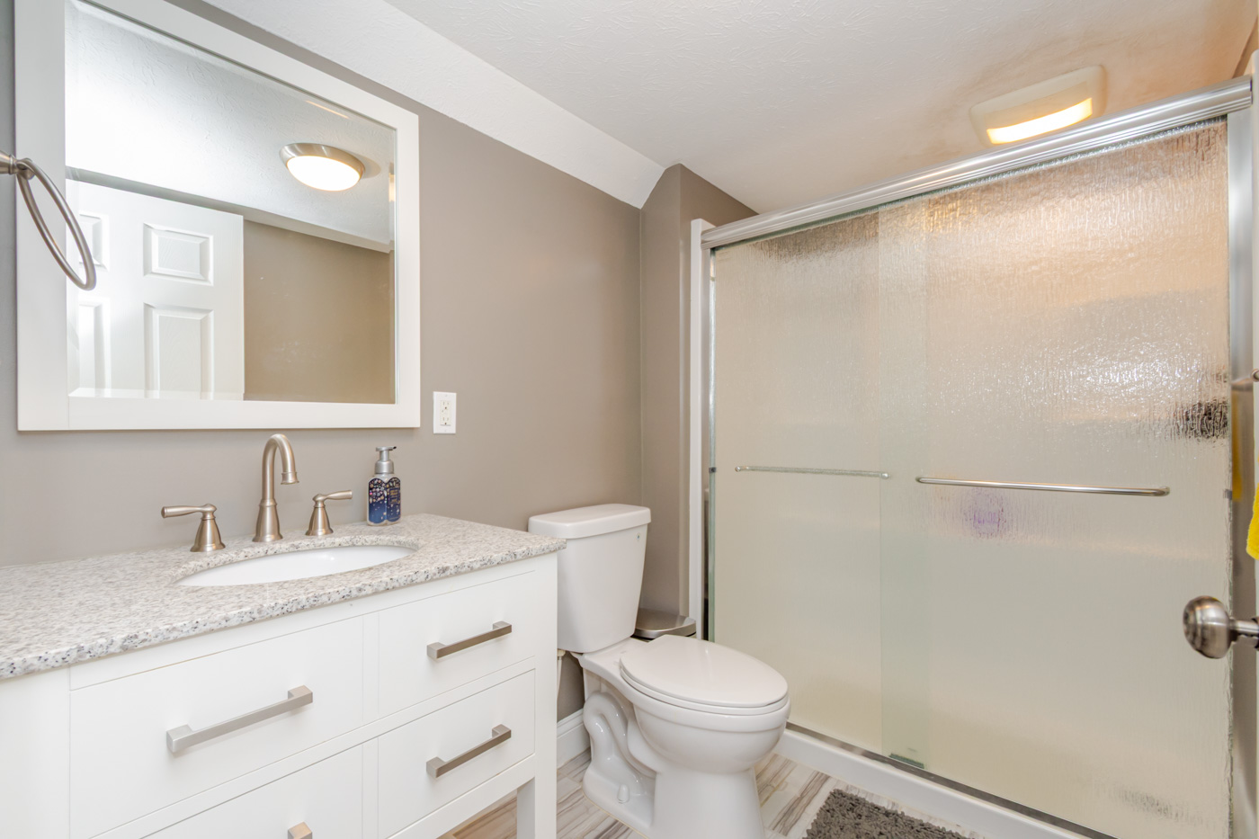 Guest bathroom with granite vanity and glass shower door