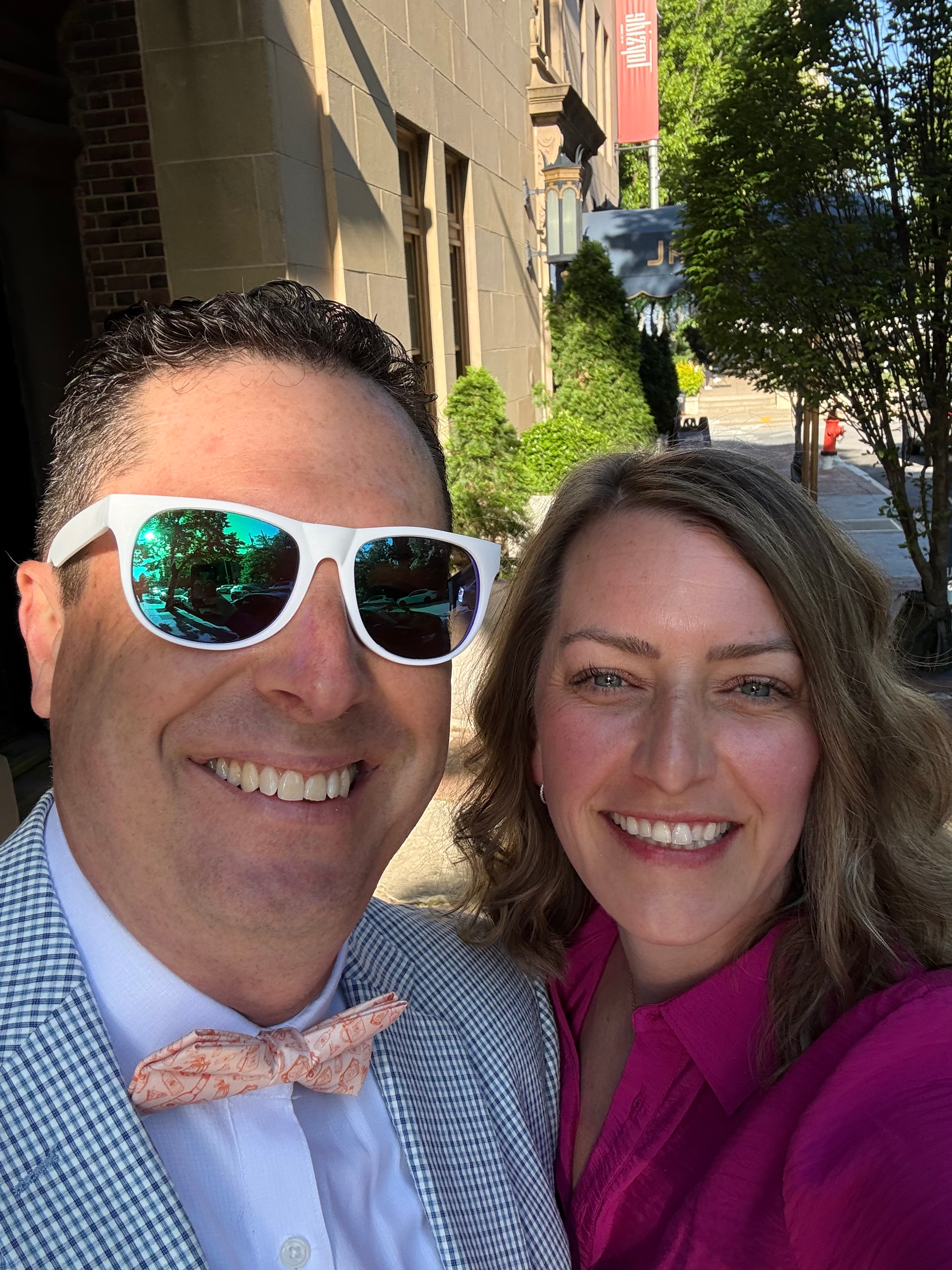 A smiling woman and man in smart-casual attire on a city street
