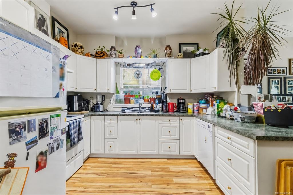 Kitchen with white shaker-style cabinetry, grey laminate countertops, and light oak hardwood flooring