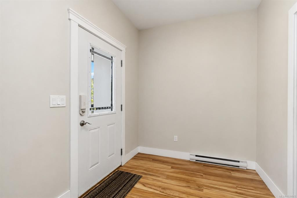 Bright front entryway with white door, glass insert, and light hardwood flooring