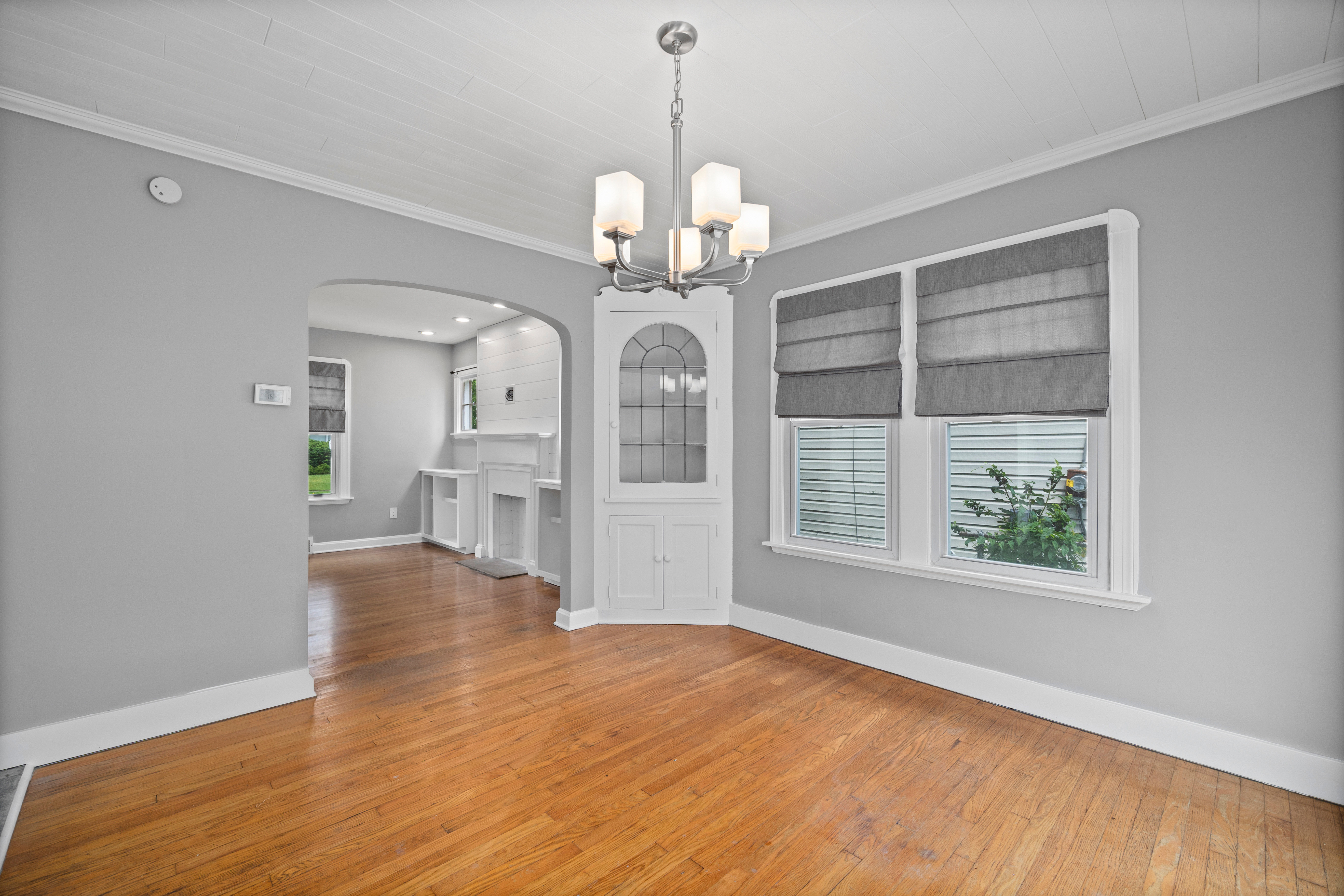 Dining room with hardwood floors, arched entryway, and white built-in china cabinet