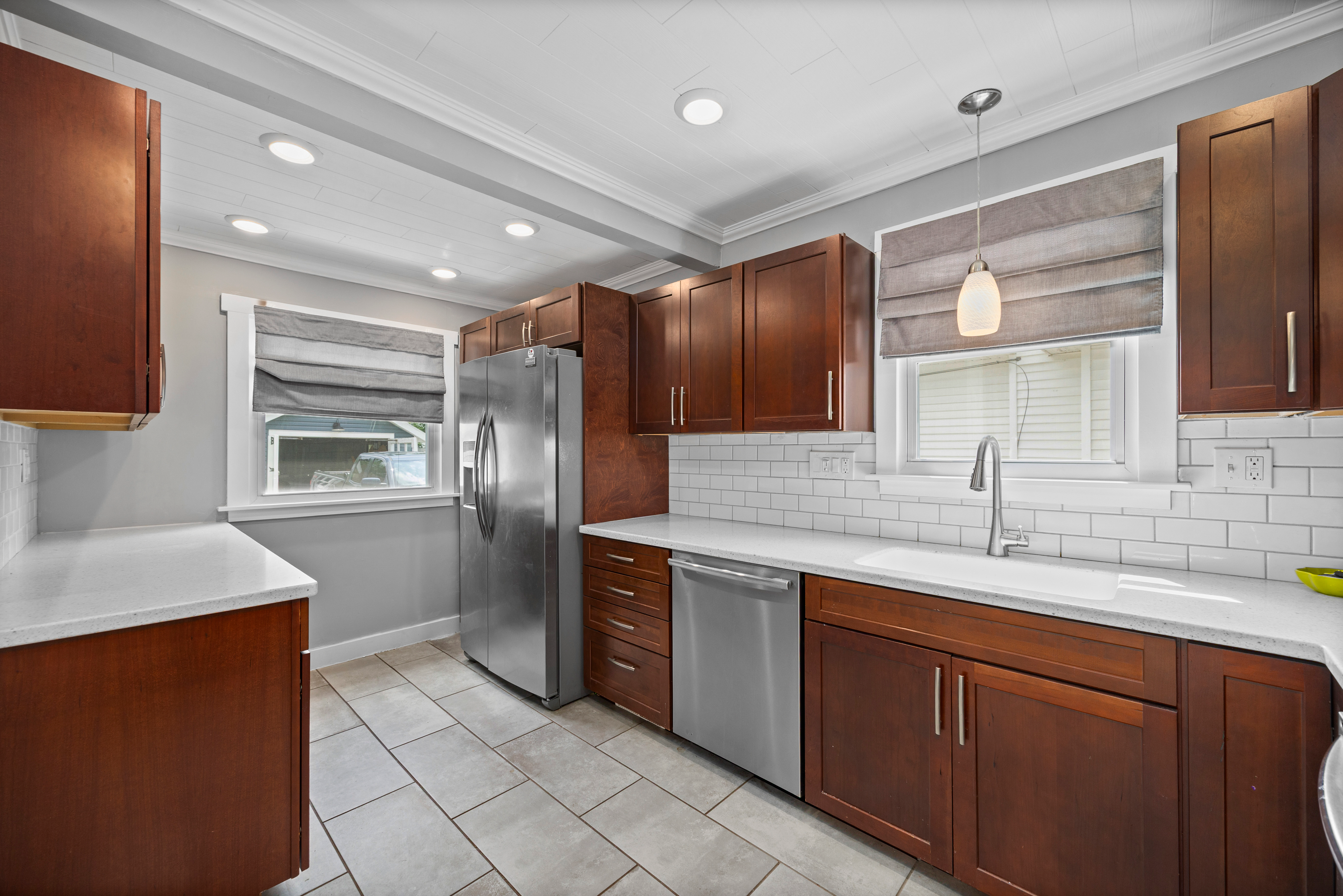 Updated kitchen with dark wood cabinets, white subway tile backsplash, and stainless steel appliances