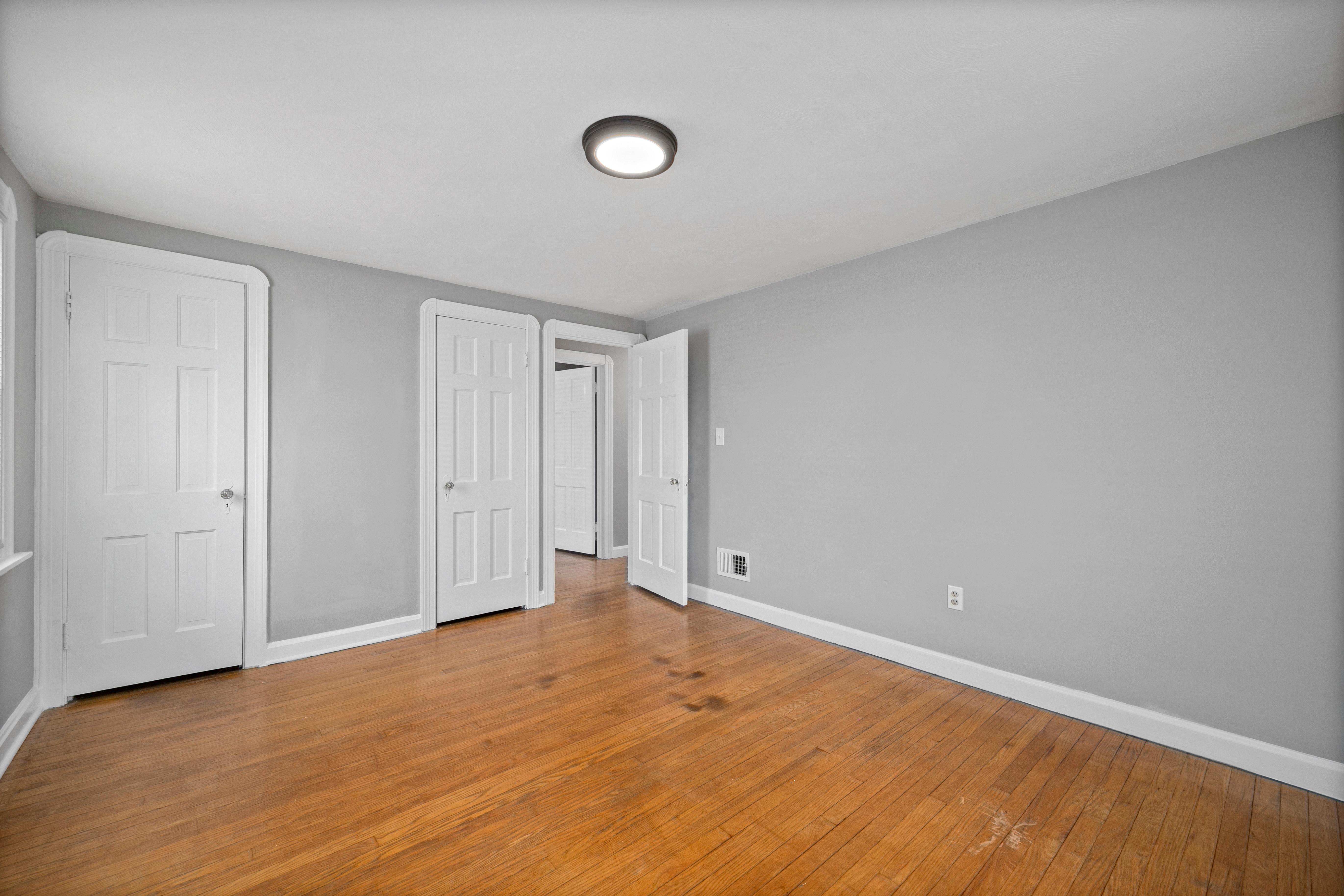 Empty bedroom with gray walls, hardwood, and arched doorway