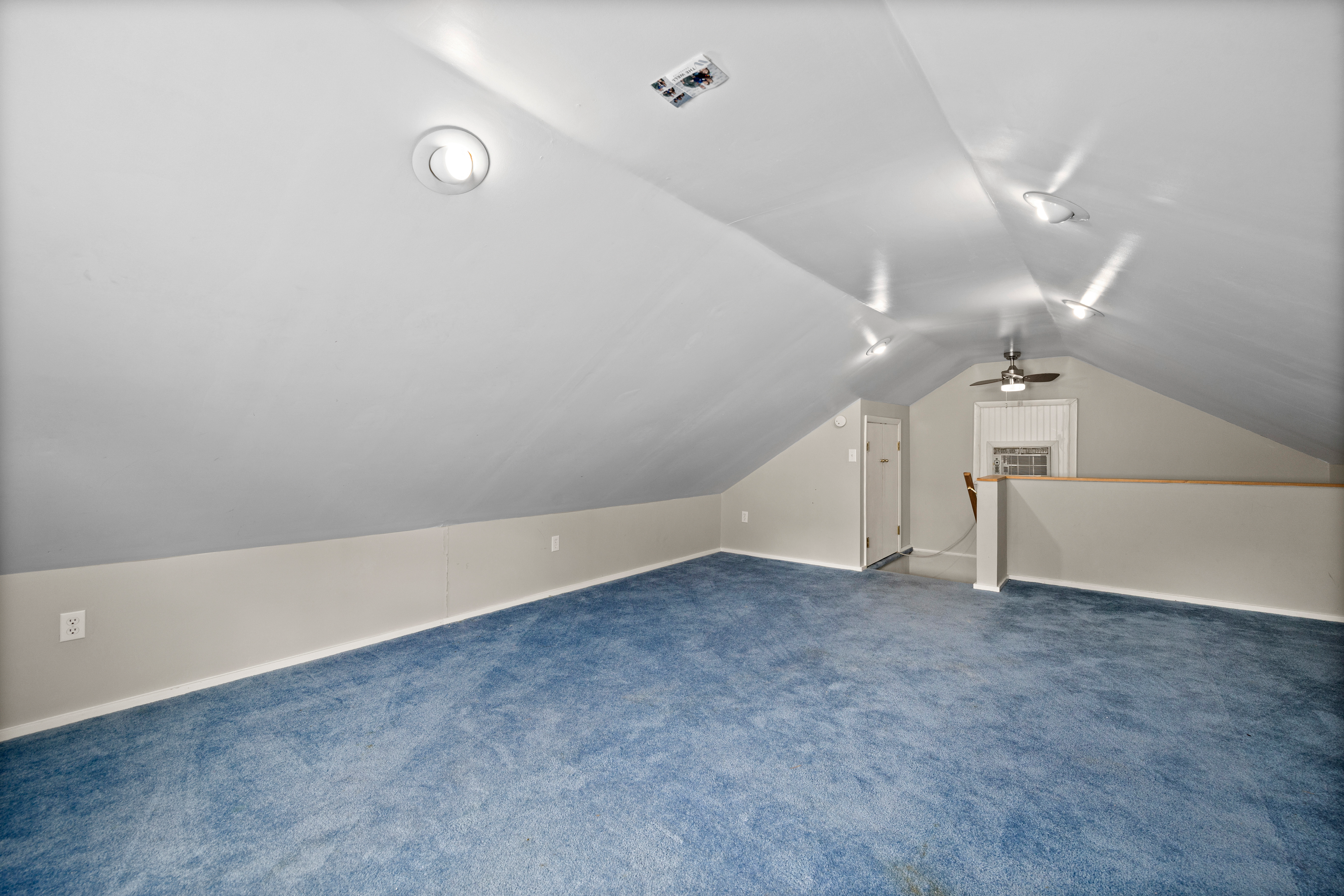 Finished attic bedroom with vaulted ceilings and blue carpeting