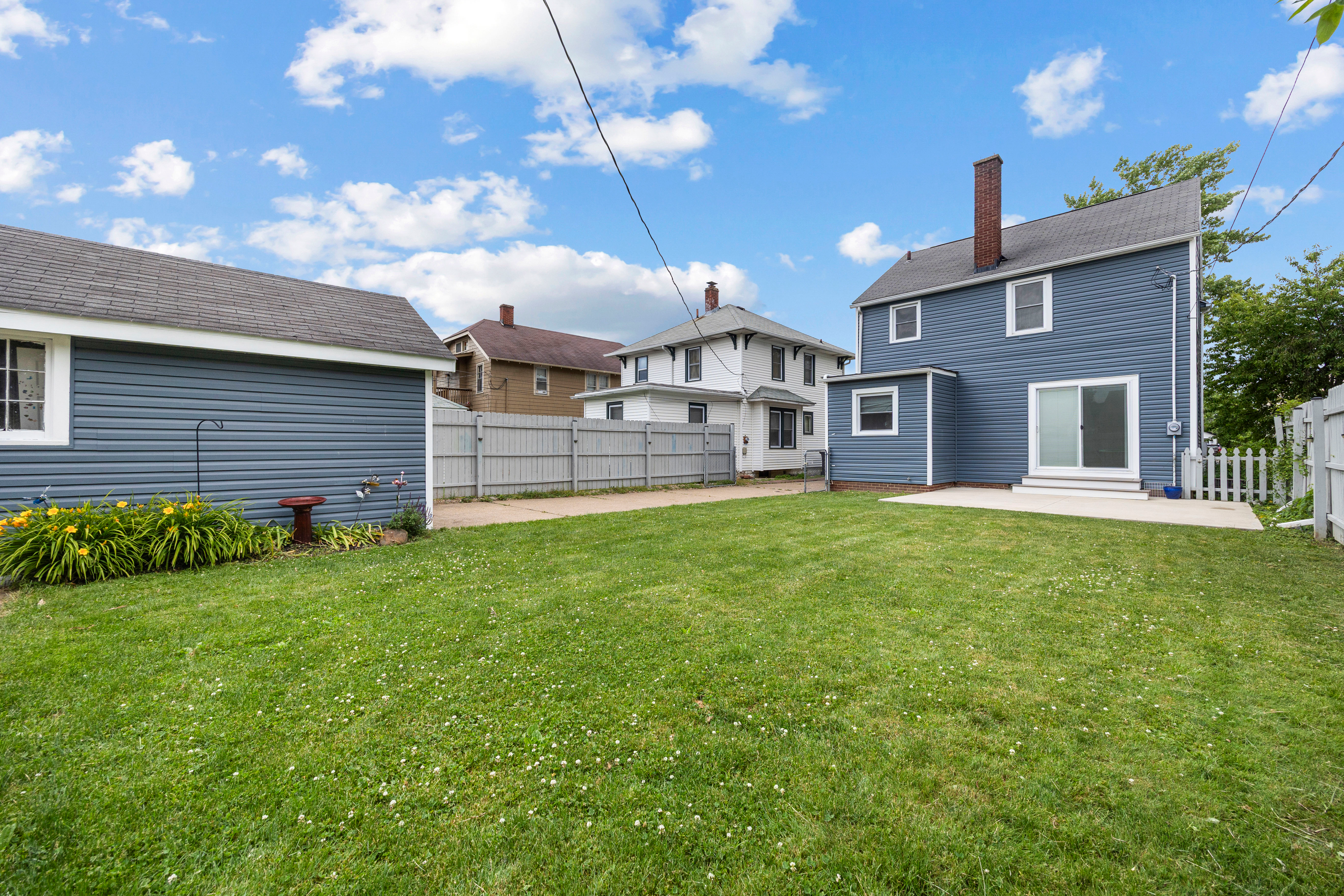 Backyard view of 337 Harvard Ave with detached garage under blue sky.