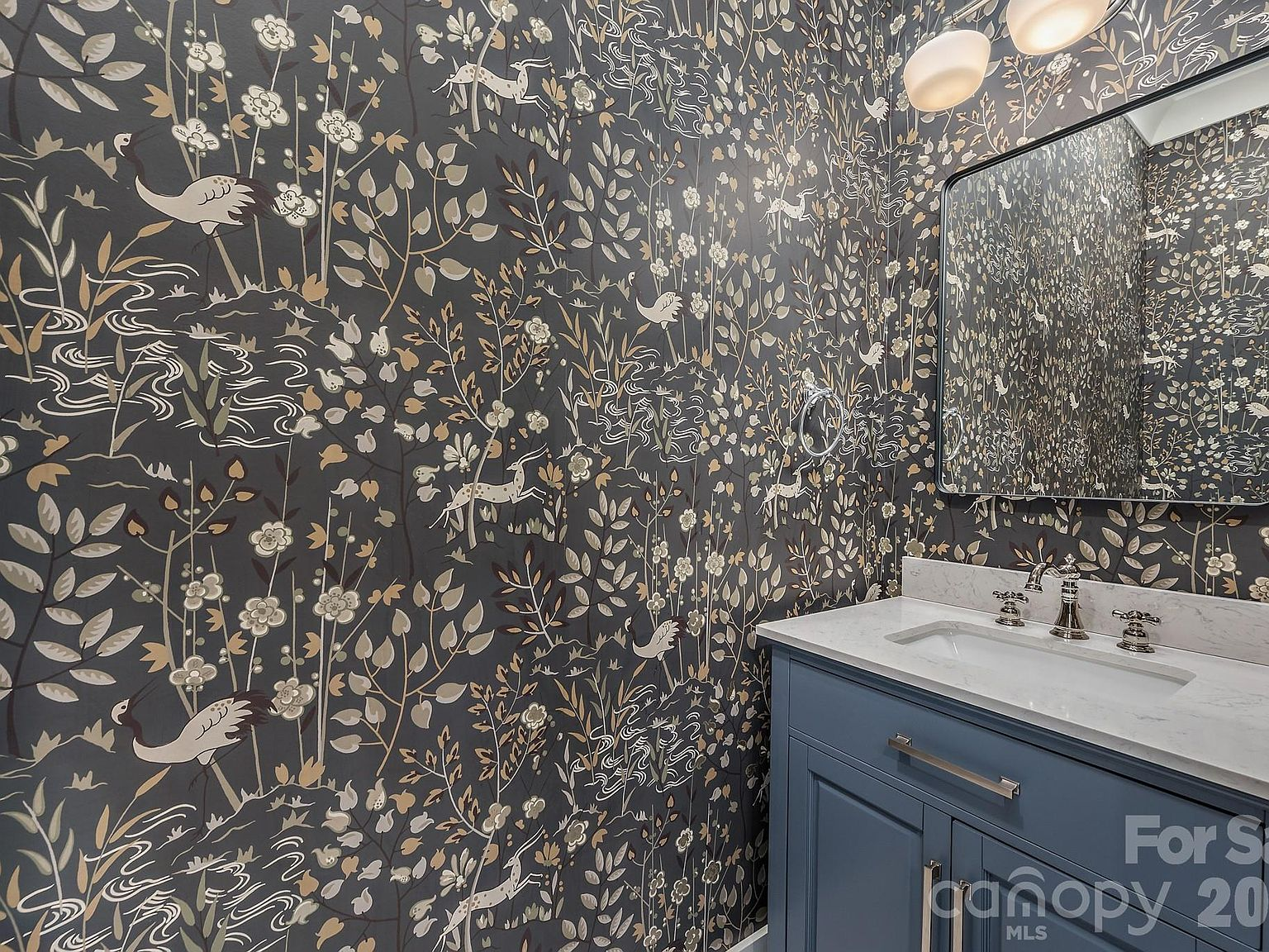 Powder room with navy vanity and ornate botanical wallpaper