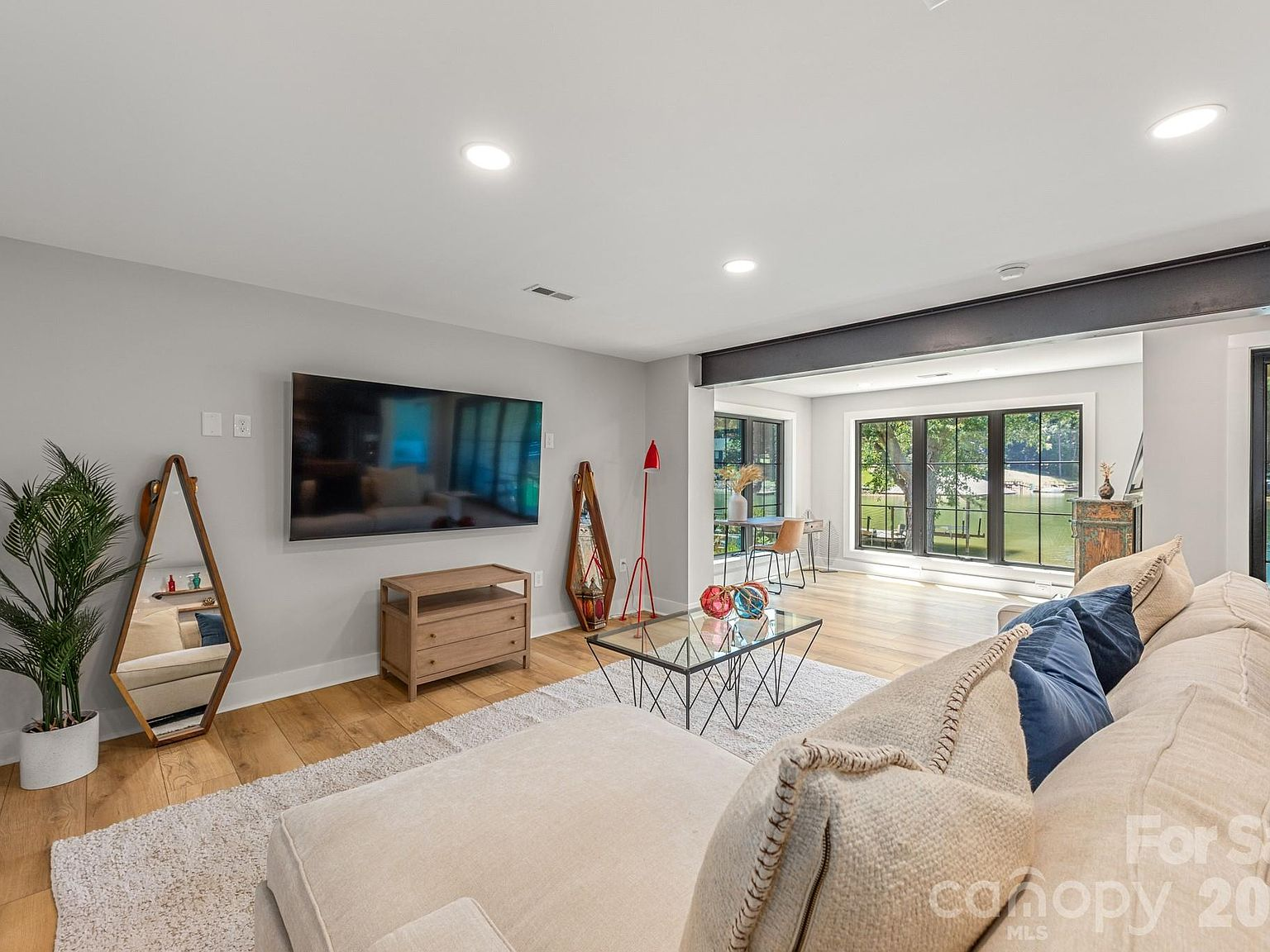 Living room with exposed steel beam and large windows overlooking the lake