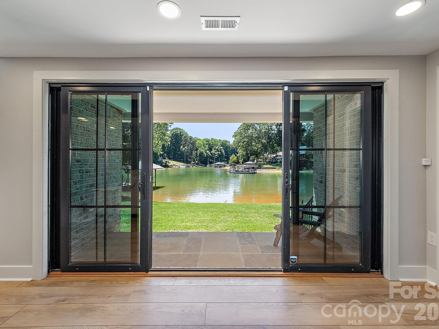 Living space looking out through wide retractable sliding glass doors to the lake