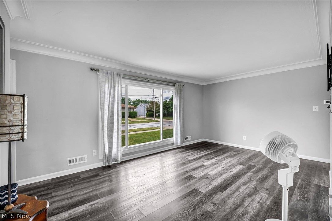 Bright living room with neutral grey walls, modern wood-look flooring, and front-facing picture window