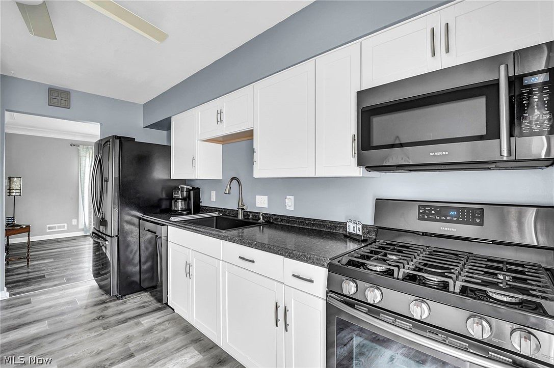 Updated kitchen with white shaker cabinets, black granite countertops, and modern appliances