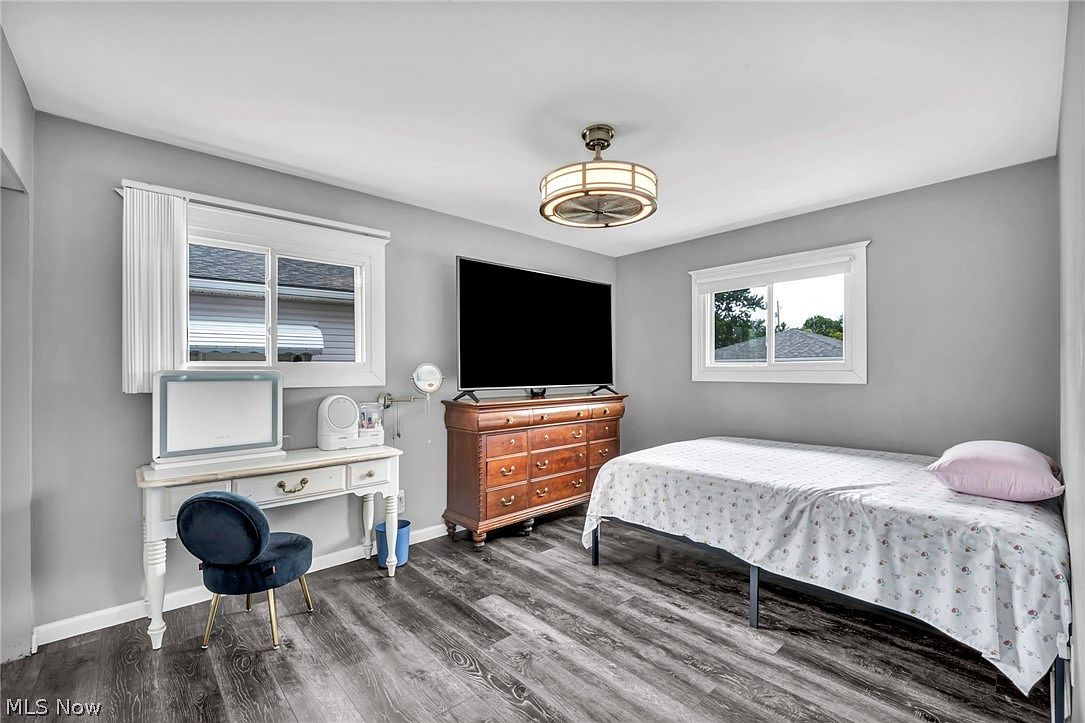 Secondary bedroom with neutral decor, light grey walls, and dark wood-look flooring