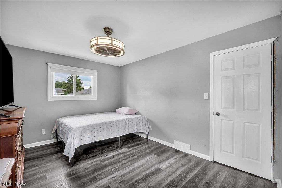 Bedroom with light gray walls and dark wood-look laminate flooring
