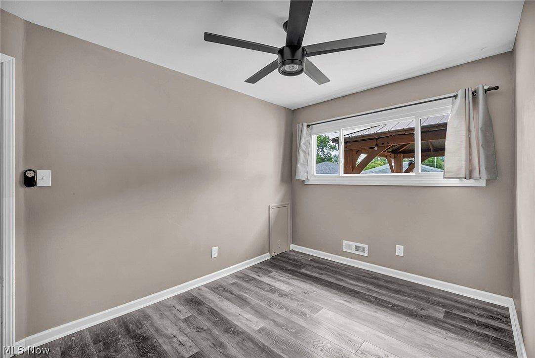 Bedroom with ceiling fan, neutral taupe walls, and grey wood-look flooring