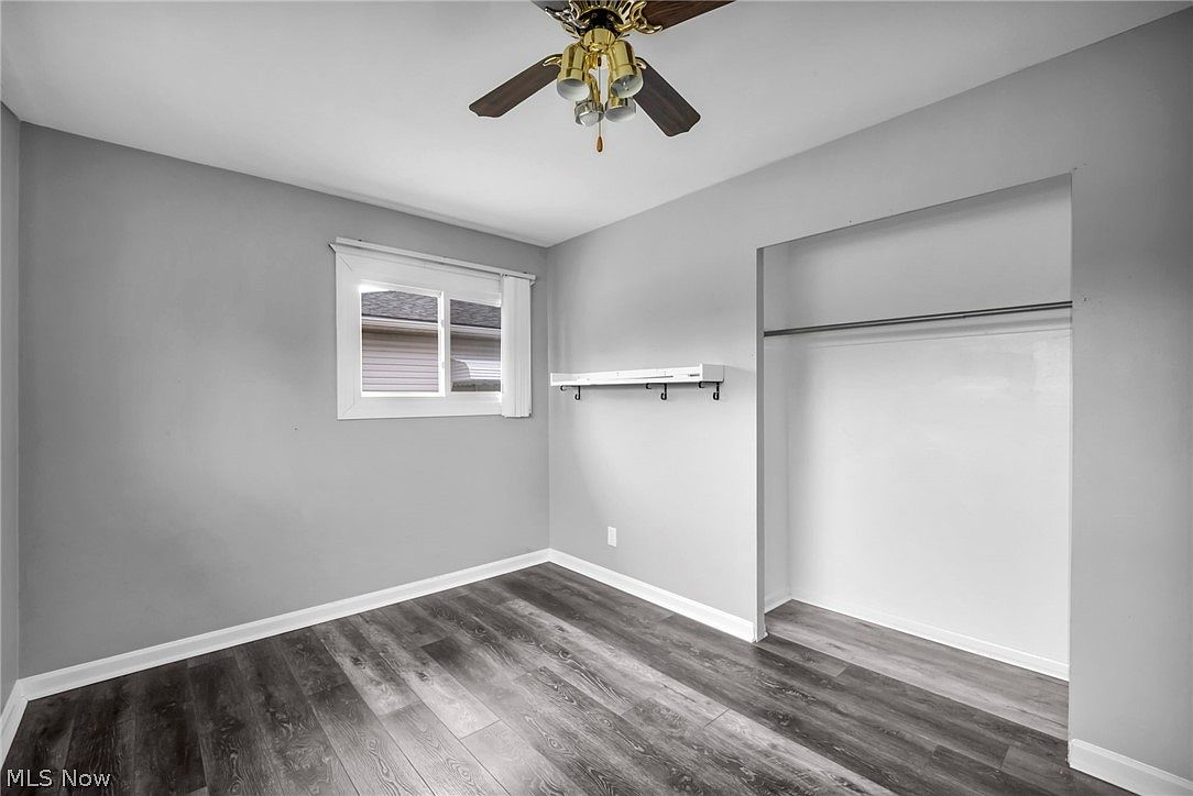 Bedroom with light gray walls, dark vinyl plank flooring, and white trim