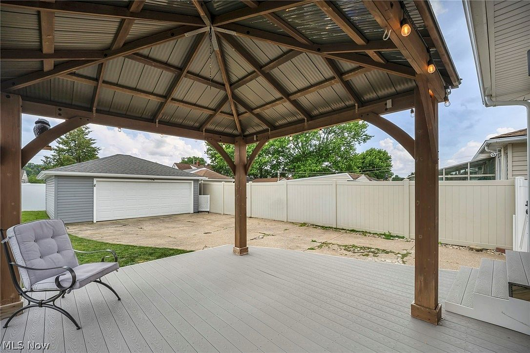 Raised deck with wooden pergola featuring metal roofing and string lights