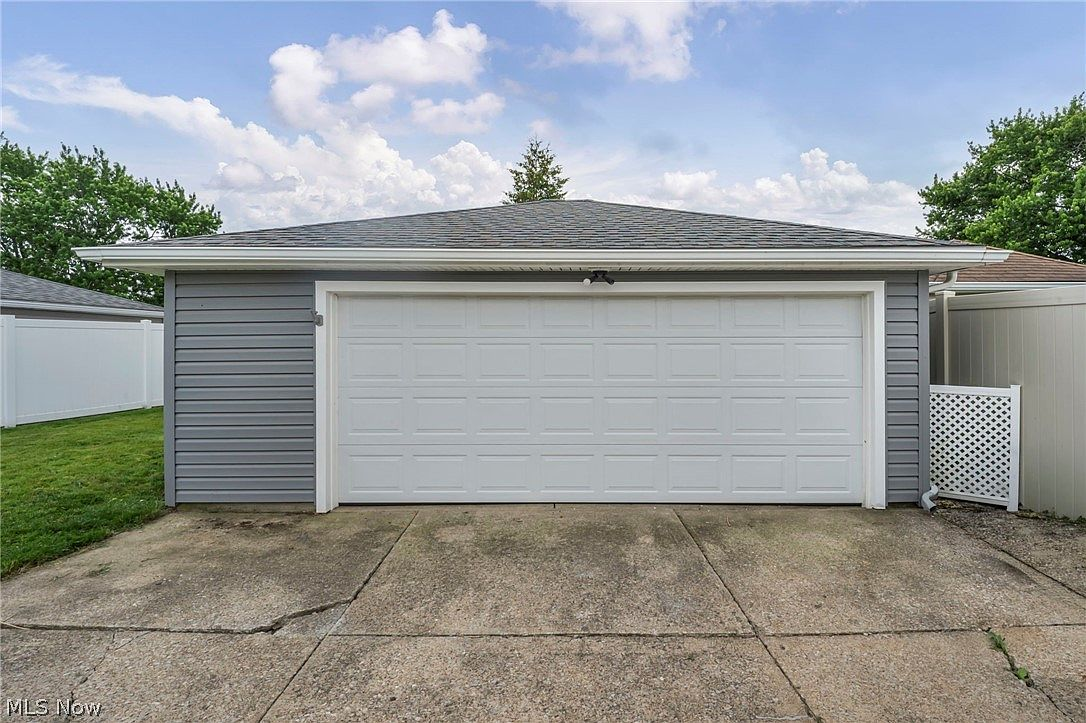 Detached two-car garage with grey vinyl siding and white garage door