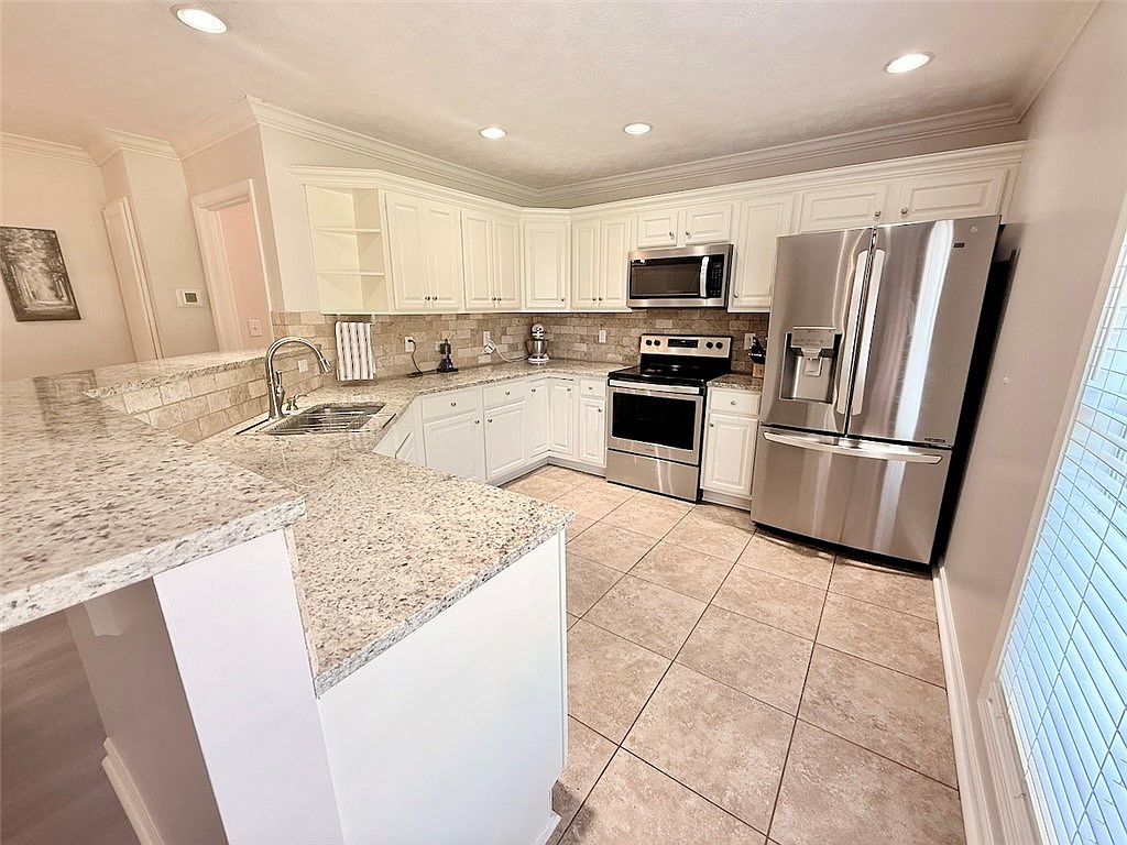 Kitchen with granite countertops, white cabinetry, and stainless steel appliances