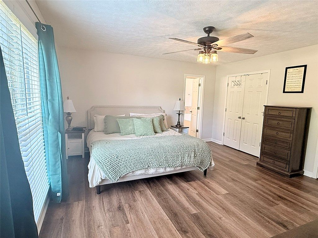 Primary bedroom suite with wood-look flooring and natural light