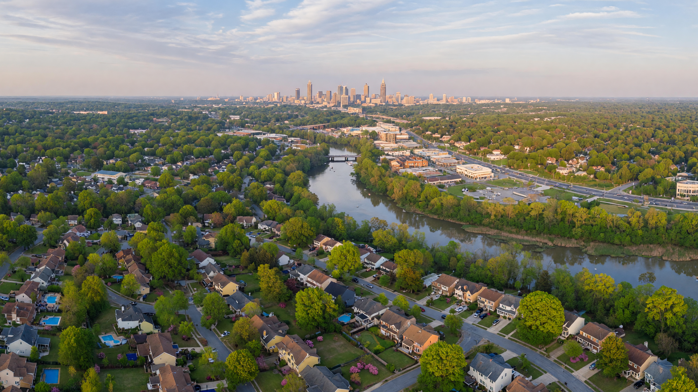 Aerial view of Atlanta suburban neighborhoods with tree-lined streets and the city skyline in the distance