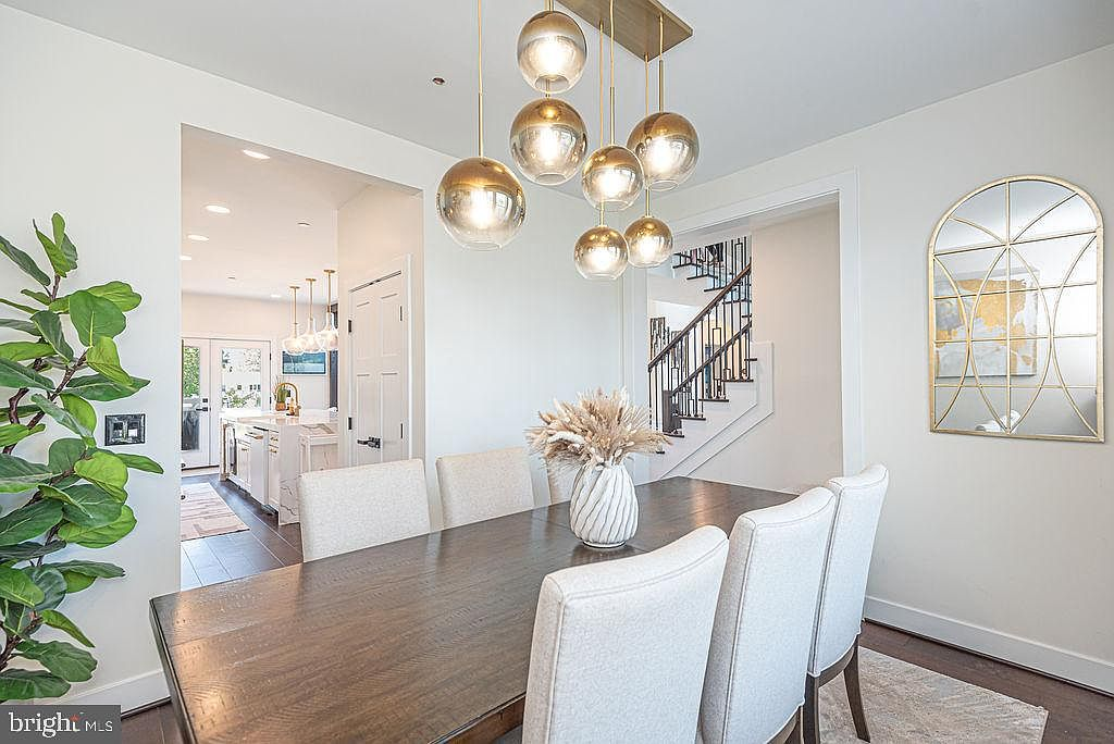 Dining area with dark wood floors and gold hardware leading to the kitchen