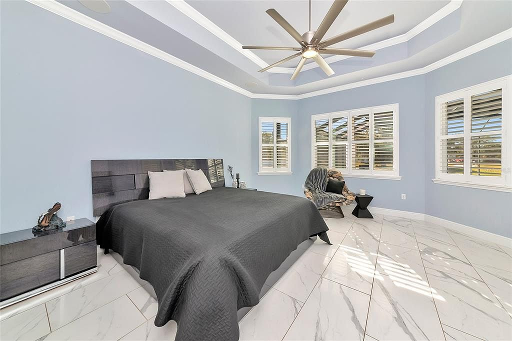 Light-filled primary suite with tray ceilings and marble-look tile