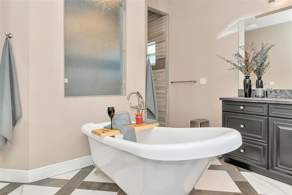 Spa-inspired bath with soaking tub, dark cabinetry and custom tile