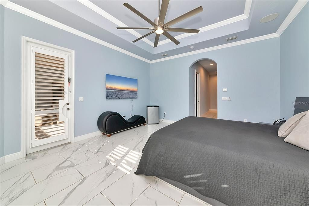 Primary suite corner with king bed, arched TV wall and lounge seating