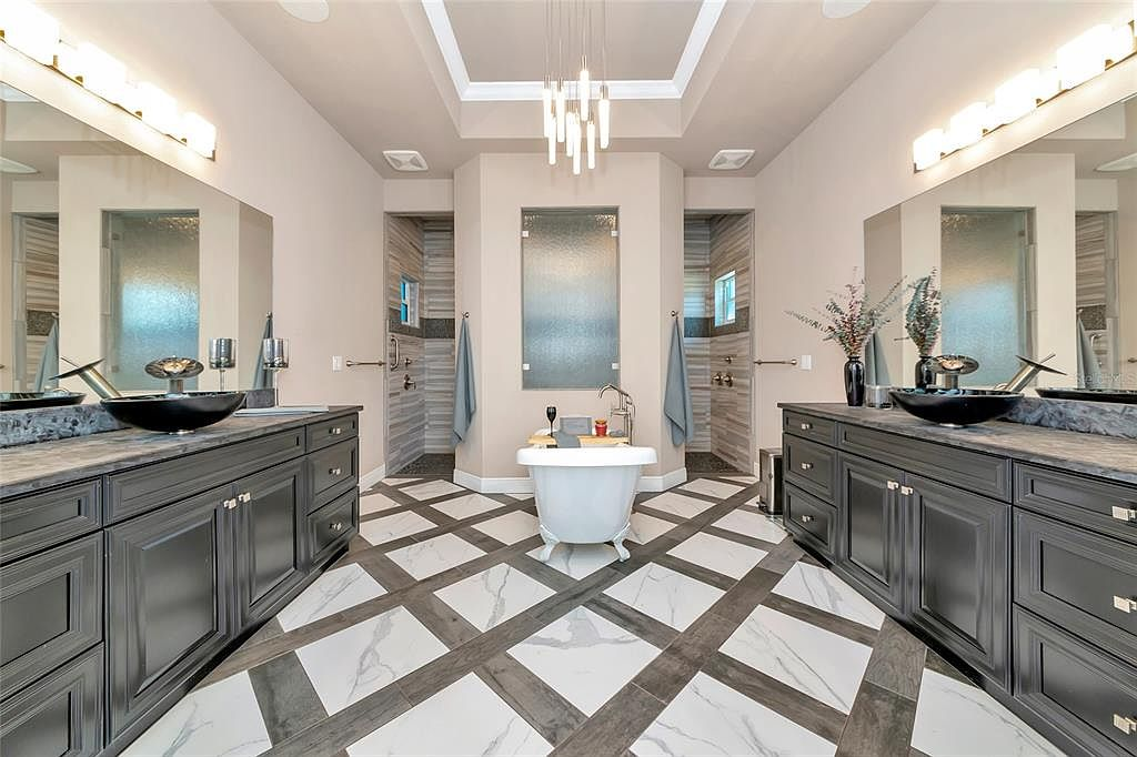 Primary bath with freestanding soaking tub, chandelier and dual vanities