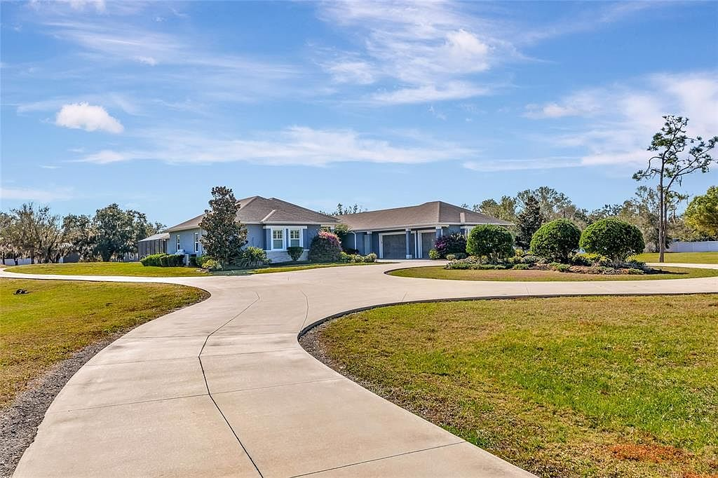 Front facade of the estate with curved driveway and multiple garage doors