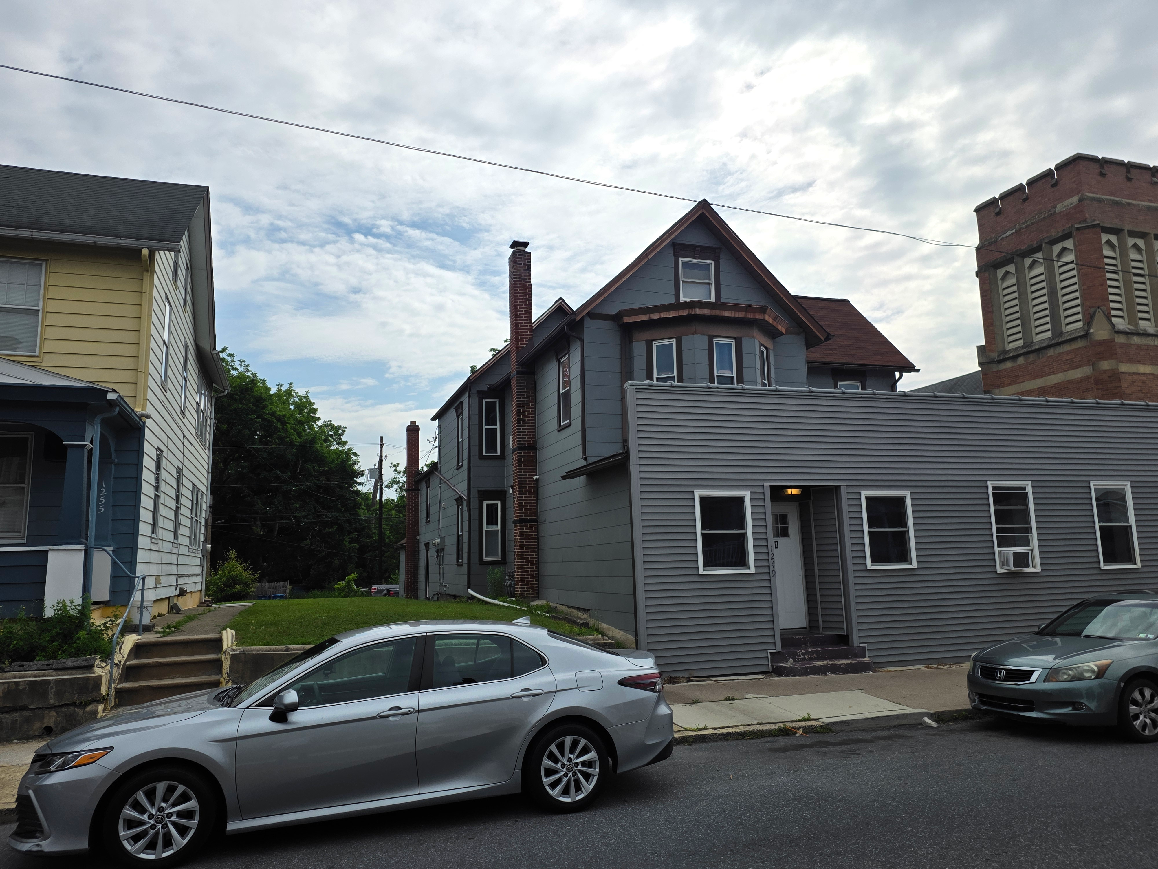 Street-level view of the exterior with grey siding and brick chimney
