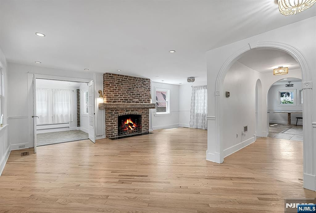 Living room with pine floors, decorative arched doorways, and wood-burning stone fireplace