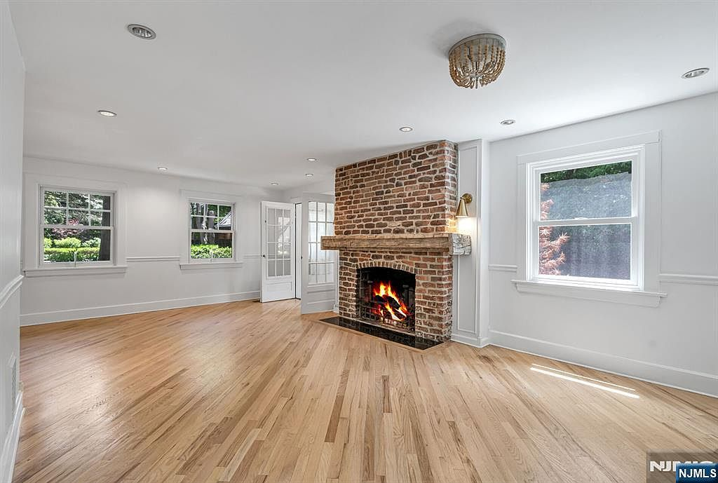 Living room with pine floors and floor-to-ceiling brick fireplace with wood mantel