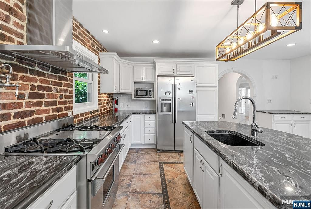 Gourmet kitchen with exposed brick backsplash, granite counters, and center island