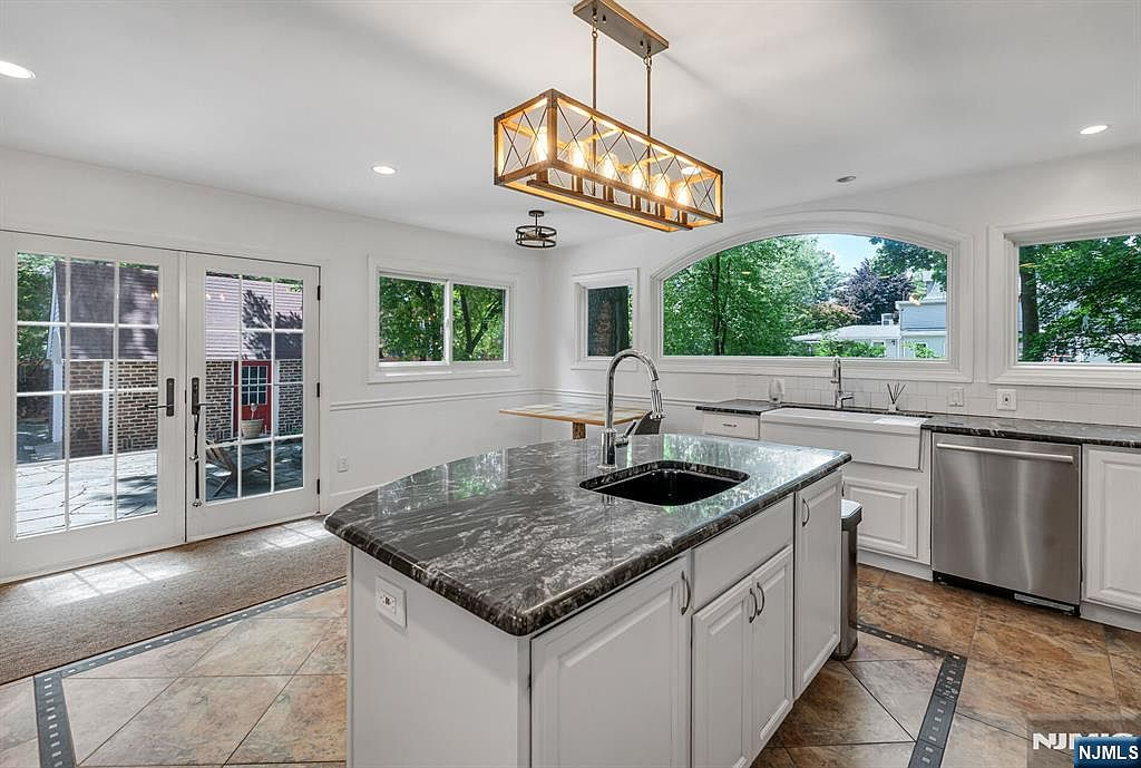 Kitchen with dark granite island, white cabinetry, and Spanish ceramic tile floor