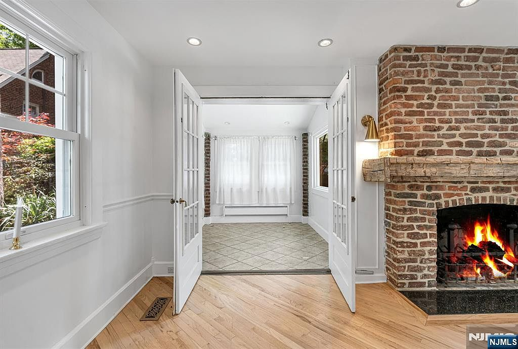 Living room fireplace with wood-burning fire and French doors to adjacent room