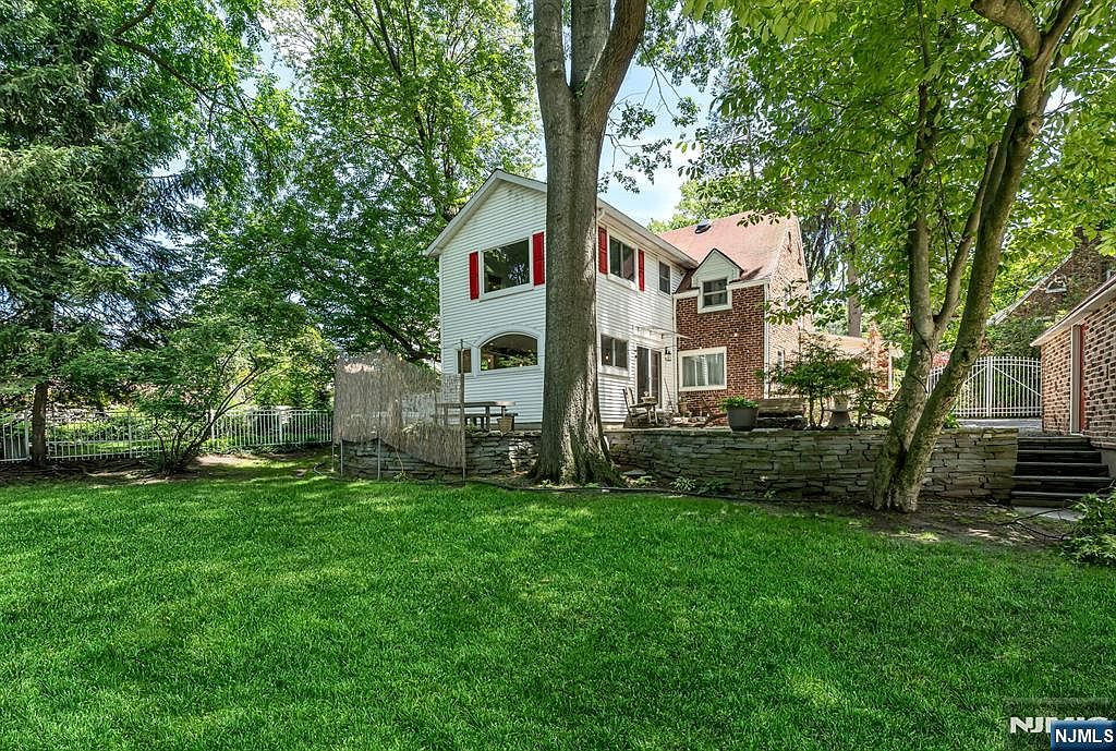 Backyard with wrap-around stone patio, retaining wall, and mature tree canopy