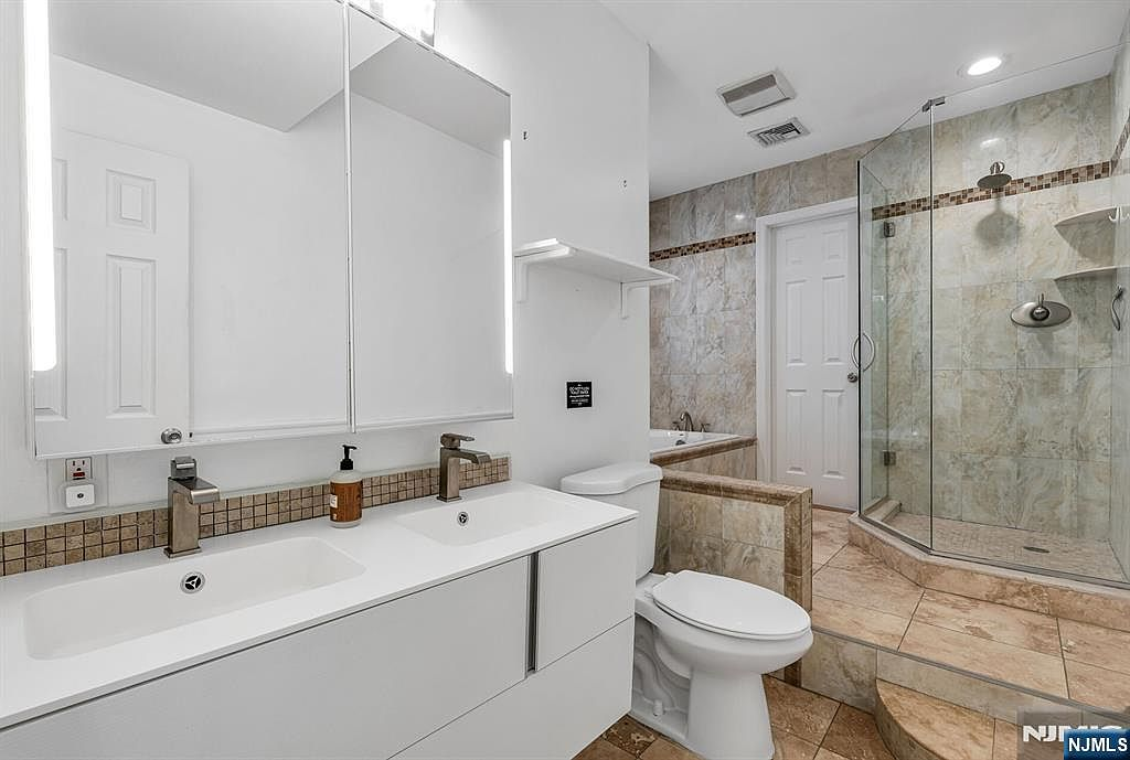 Primary bathroom with double-sink vanity, porcelain tile, and glass shower enclosure