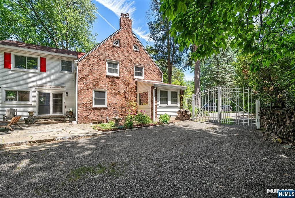 Rear facade with red brick, white siding, and slate patio