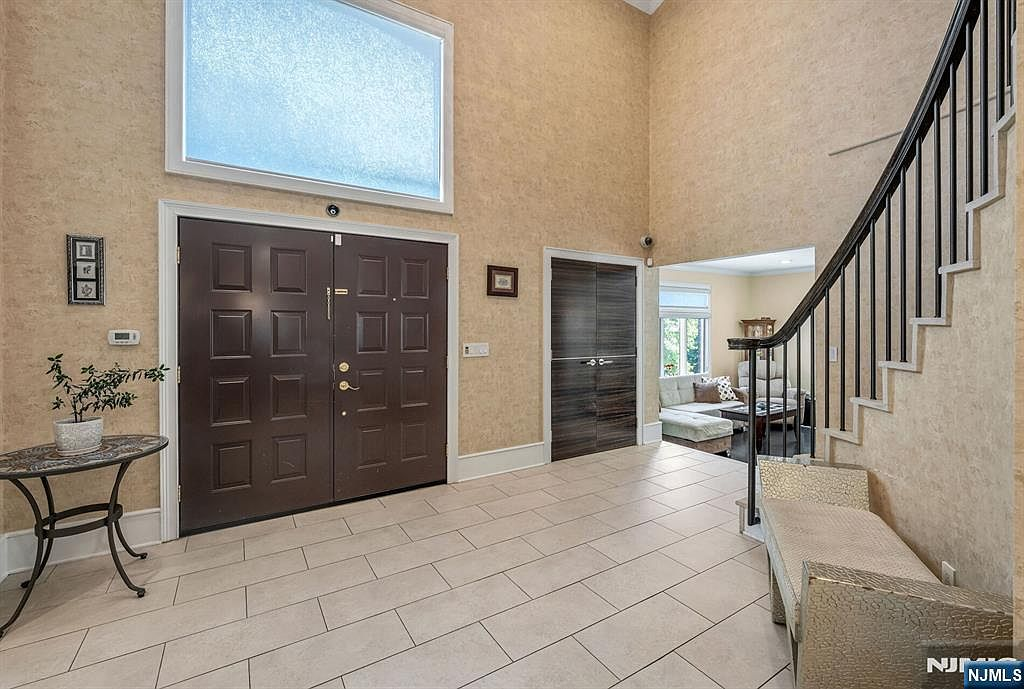 Two-story foyer with Venetian plaster walls, custom Wenge doors, and ironwork stair railing