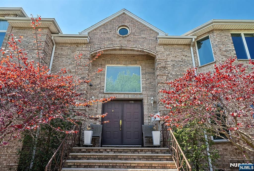 Front entry with limestone steps, dark double doors, and flowering ornamental trees