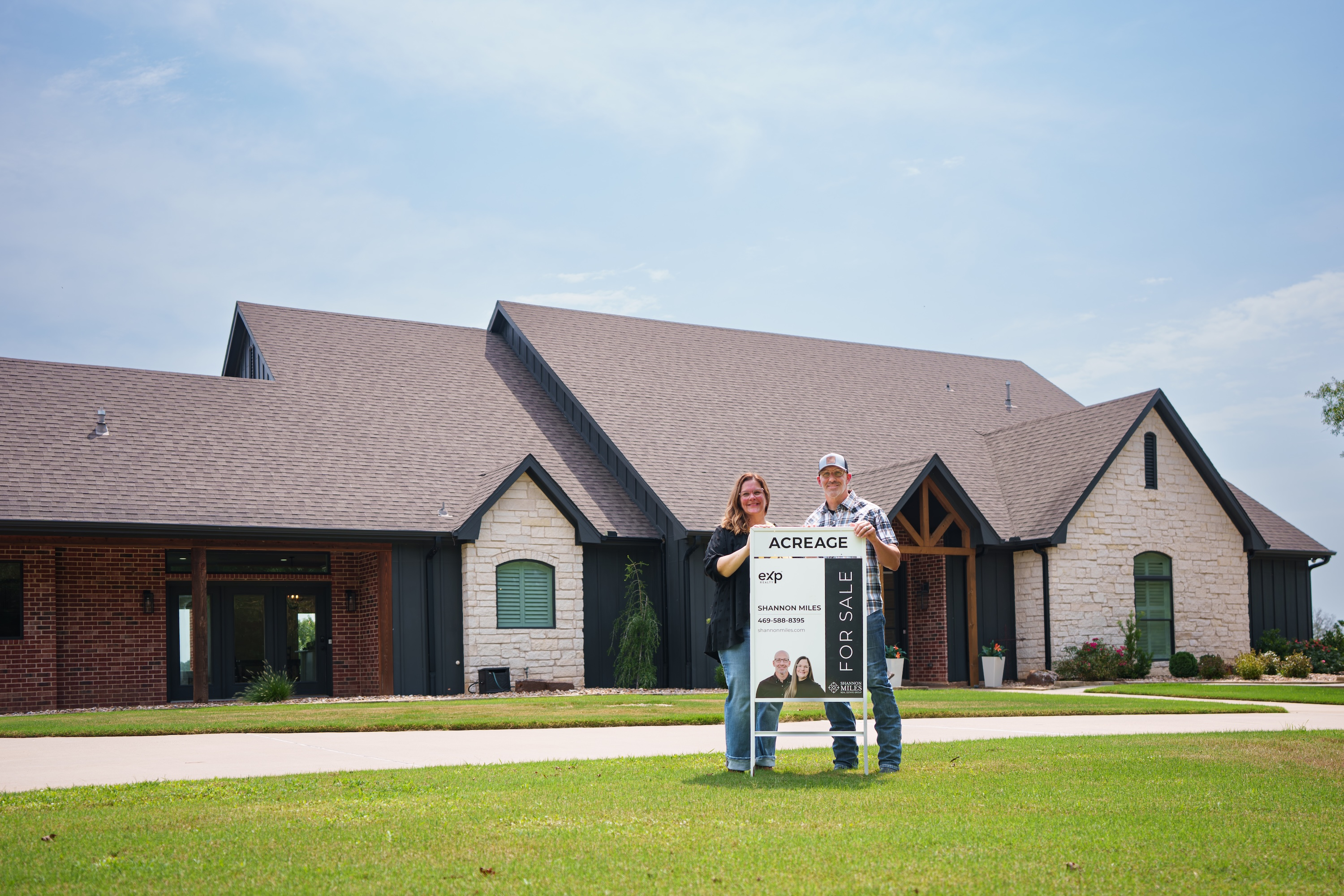 Shannon and Scott Miles standing in front of a listed home beside an eXp Realty sign