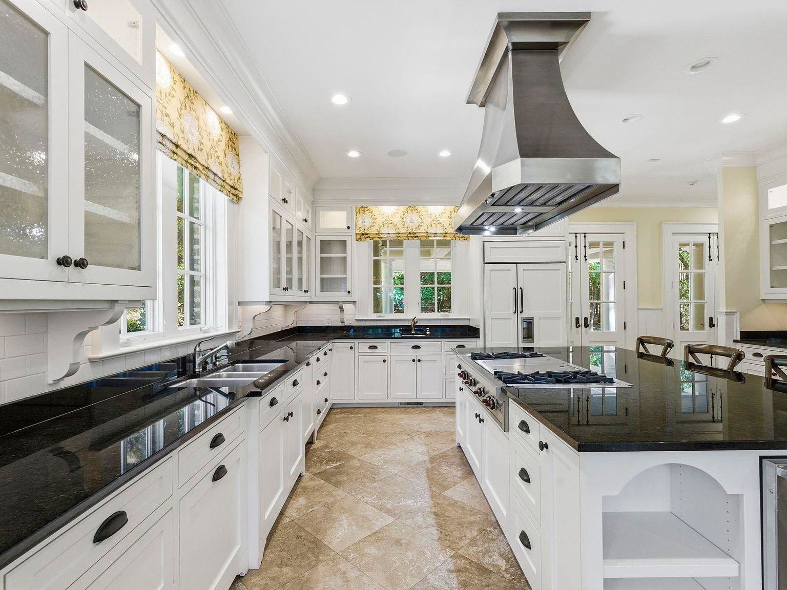 White kitchen with granite countertops and natural stone tile floors