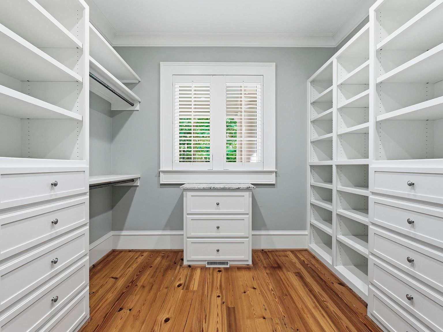 Custom walk-in closet with white built-ins and heart pine flooring