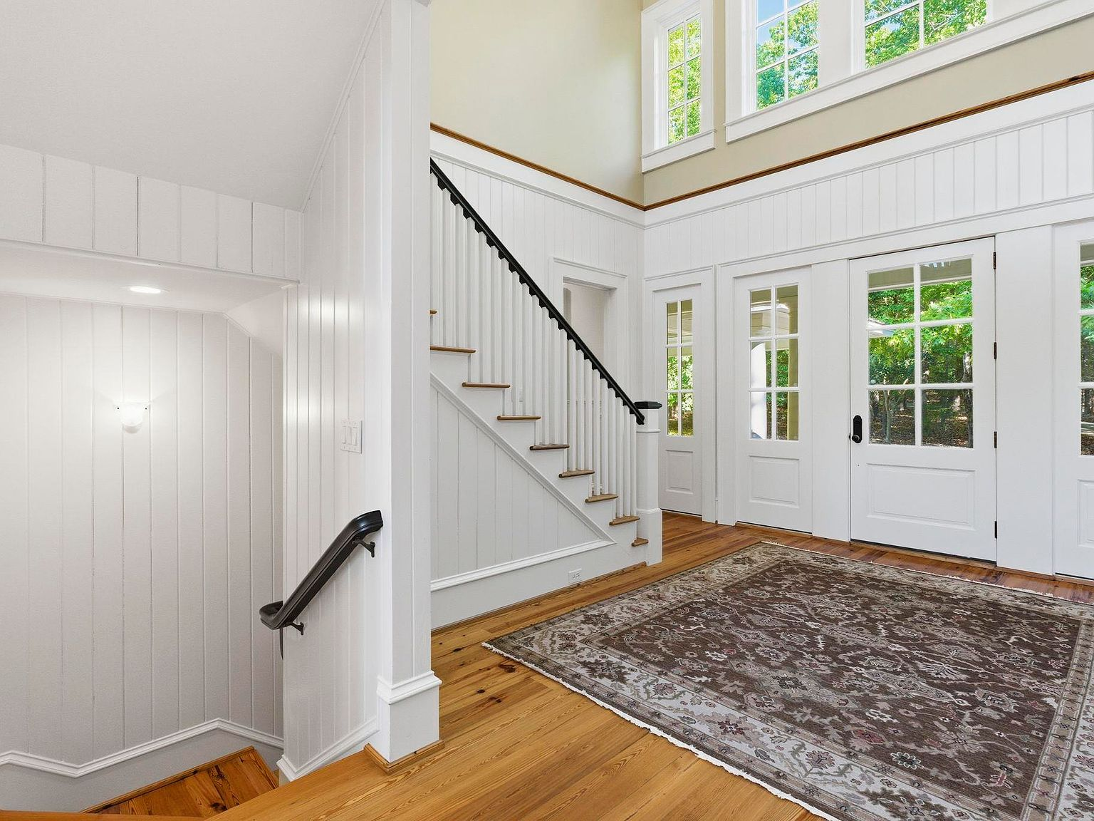 Foyer with board-and-batten walls, heart pine floors, and iron staircase