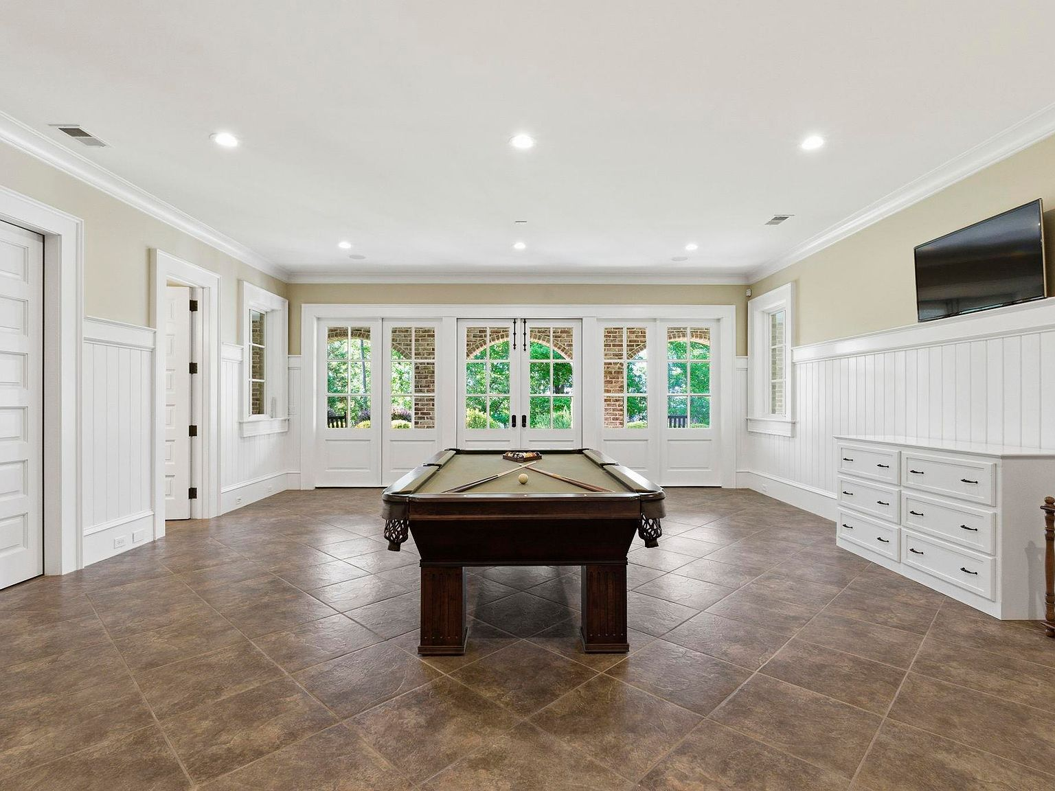Finished basement recreation room with pool table and brick arch views