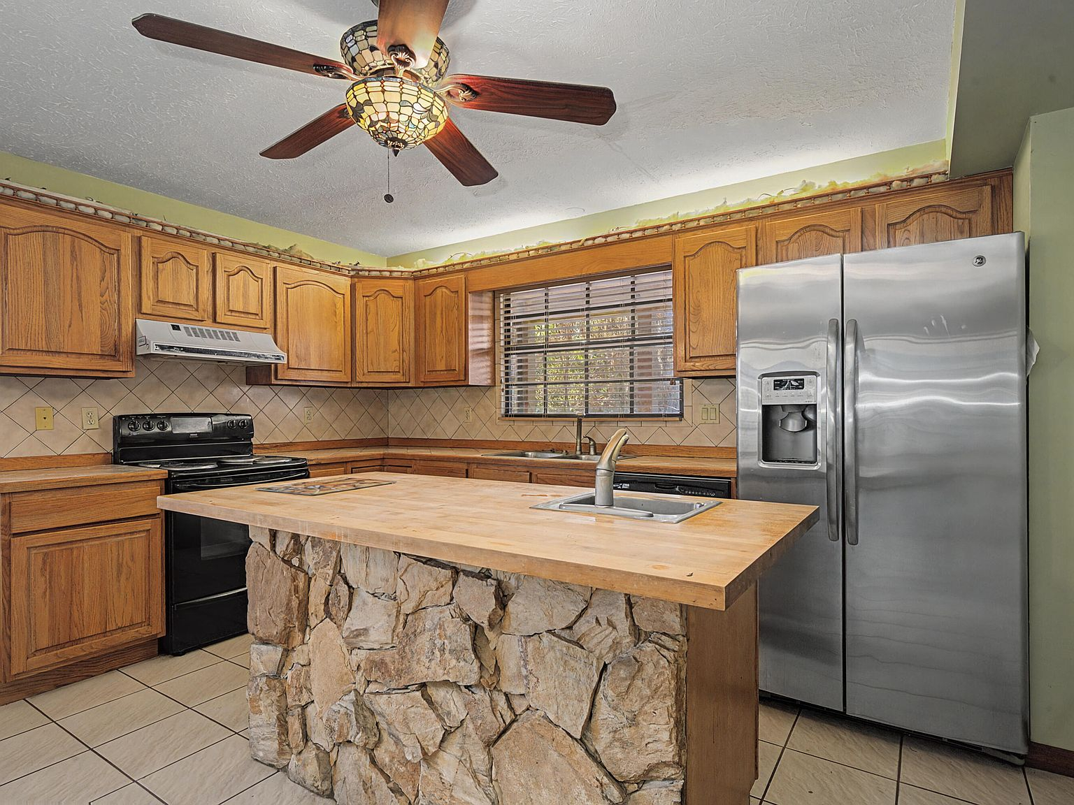 Kitchen with stone-veneer island and oak cabinetry