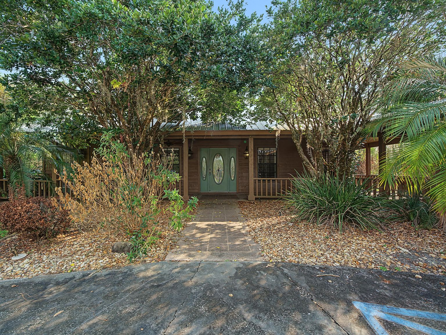 Front facade of 665 Moon Ranch Road showing wood-sided ranch home with metal roof and wrap-around porch